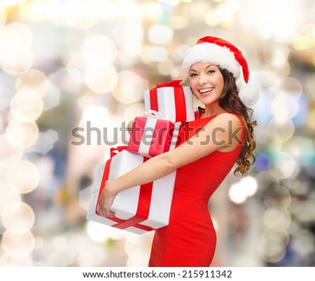 christmas, holidays, celebration and people concept - smiling woman in red dress with gift boxes over lights background