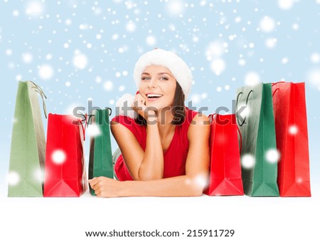 sale, gifts, christmas, x-mas concept - smiling woman in red shirt and santa helper hat with shopping bags