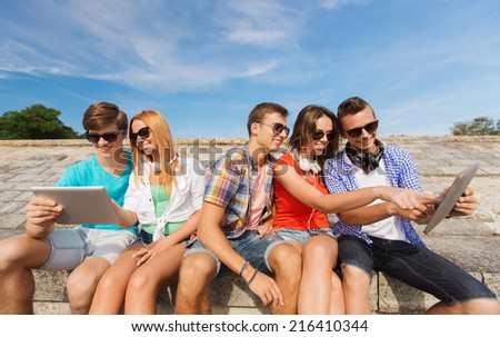 friendship, leisure, summer and people concept - group of smiling friends with tablet pc computers sitting outdoors