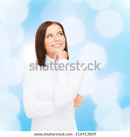 clothing, winter holidays, christmas and people concept - smiling young woman in white sweater over blue lights background