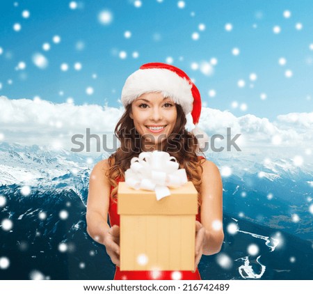 christmas, holidays, celebration and people concept - smiling woman in red dress with gift box over blue snowy background