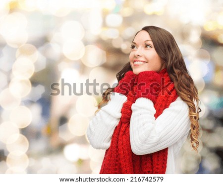 happiness, winter holidays, christmas and people concept - smiling young woman in red scarf and mittens over lights background