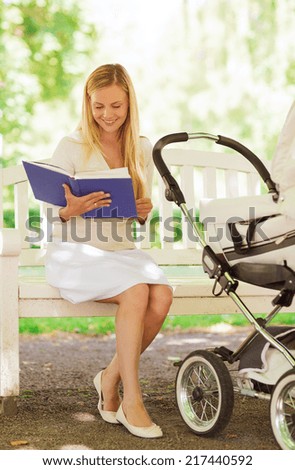 family, child, leisure, education and parenthood concept - happy mother with baby stroller reading book in park