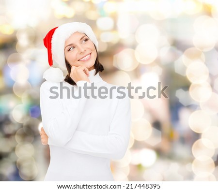 christmas, holidays, winter, happiness and people concept - thinking and smiling woman in santa helper hat over lights background