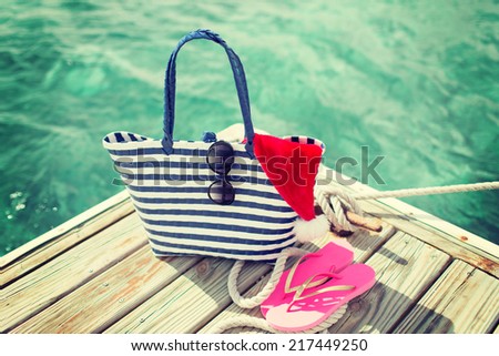 beach, summer, vacation, christmas and accessories concept - close up of beach accessories and santa helper hat on wooden pier