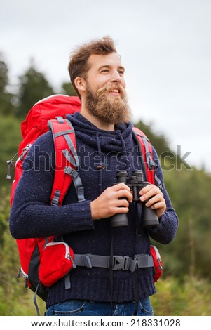 adventure, travel, tourism, hike and people concept - smiling man with red backpack and binocular outdoors