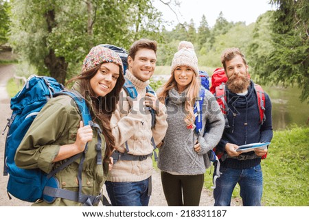 adventure, travel, tourism, hike and people concept - group of smiling friends with backpacks and map outdoors