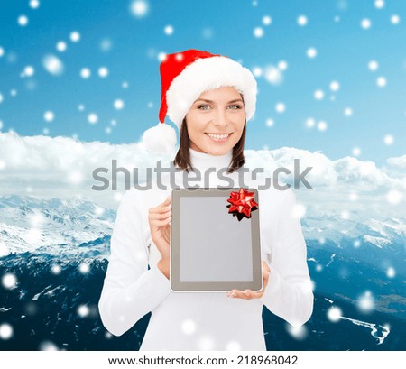 christmas, technology, present and people concept - smiling woman in santa helper hat with blank screen tablet pc computer over snowy mountains background