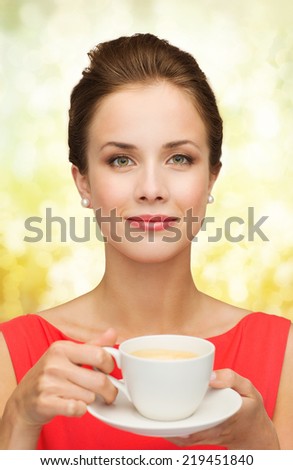leisure, happiness and drink concept - smiling woman in red dress with cup of coffee over golden lights background