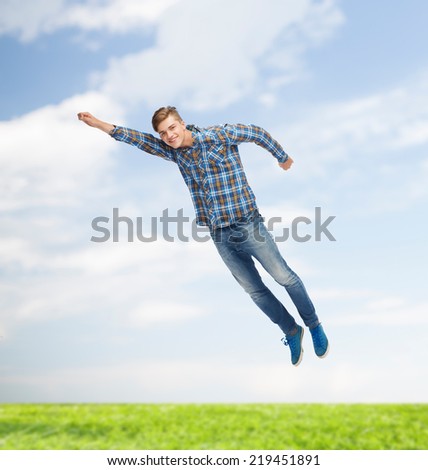 happiness, freedom, vacation, summer and people concept - smiling young man flying in air over natural background