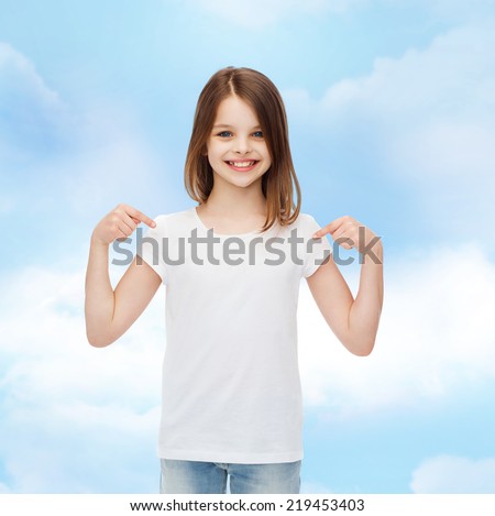 advertising, dream, childhood, gesture and people - smiling little girl in white t-shirt pointing fingers on herself over cloudy sky background