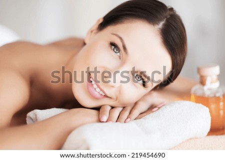 beauty and spa concept - happy woman in spa salon lying on the massage desk