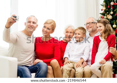 family, holidays, generation, christmas and people concept - smiling family with camera making selfie and sitting on couch at home