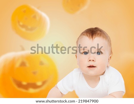holidays, childhood, happiness and people concept - smiling baby over pumpkins background