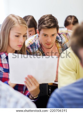 education, high school, teamwork and people concept - group of students with papers or test on exam