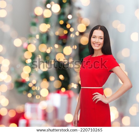 holidays, celebration and people concept - smiling woman in red dress over christmas tree background