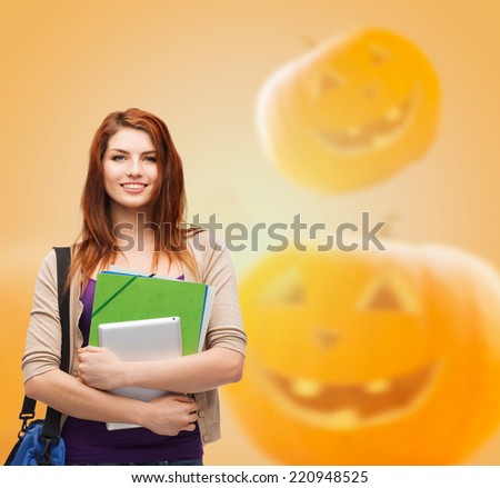 education, holidays, school and people concept - smiling student girl with books and bag over halloween pumpkins background