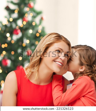 christmas, x-mas, happiness concept - mother and daughter whispering secret