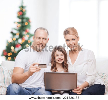 family, holidays, shopping, technology and people - happy family with laptop computer and credit card over living room and christmas tree background
