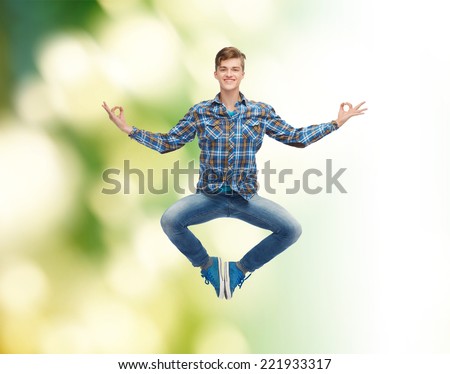 happiness, freedom, movement, ecology and people concept - smiling young man hanging of flying in air in pose of yoga over green background