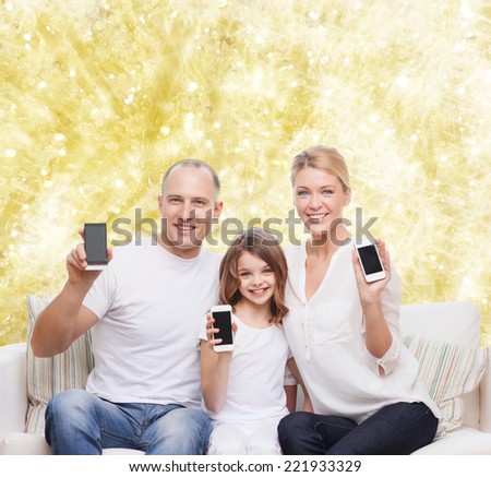holidays, technology, advertisement and people concept - smiling family with smartphones over yellow lights background