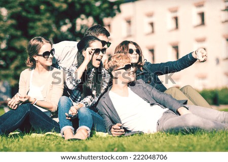 summer holidays and teenage concept - group of teenagers taking photo outside with smartphone