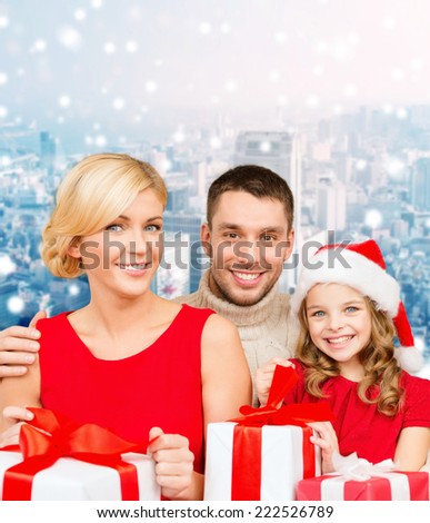 christmas, holidays, family and people concept - happy mother, father and little girl in santa helper hat with gift boxes over snowy city background