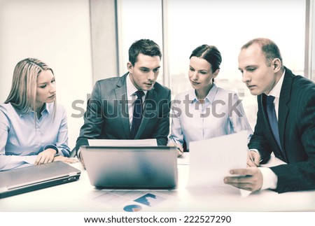 business, technology and office concept - concentrated business team with laptop computers and documents having discussion in office