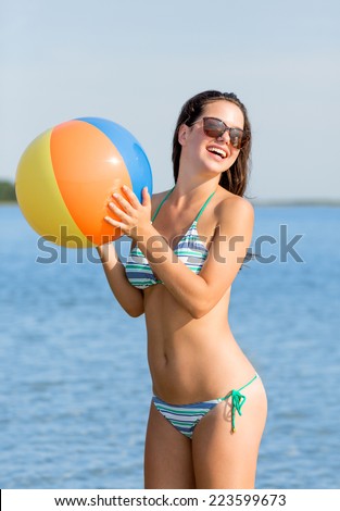 sea, summer vacation, holidays, sport and people concept - smiling teenage girl in sunglasses with inflatable ball on beach
