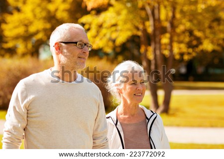 family, age, tourism, travel and people concept - senior couple walking in city park