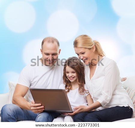 family, childhood, holidays, technology and people concept - smiling family with laptop computer over blue lights background