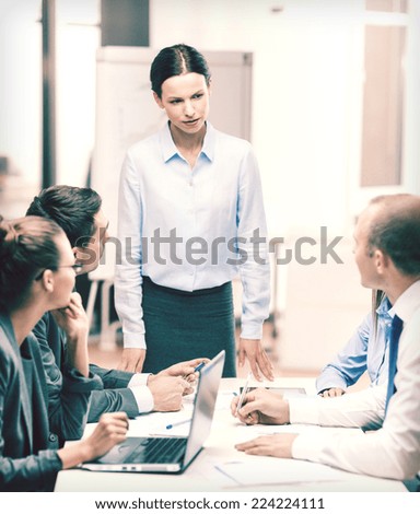 business, technology and office concept - strict female boss talking to business team