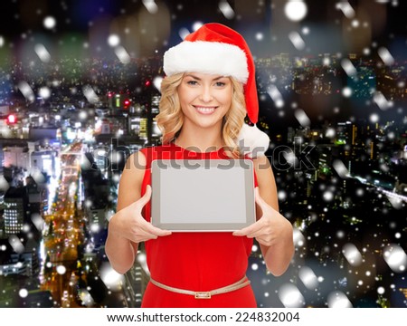 christmas, technology, present and people concept - smiling woman in santa helper hat with tablet pc computer showing blank screen over snowy night city background