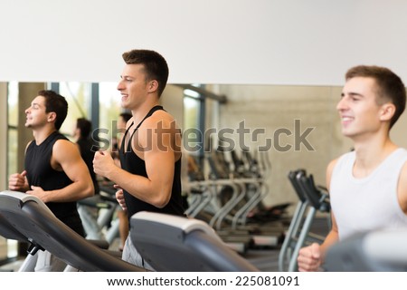 sport, fitness, lifestyle, technology and people concept - smiling men exercising on treadmill in gym