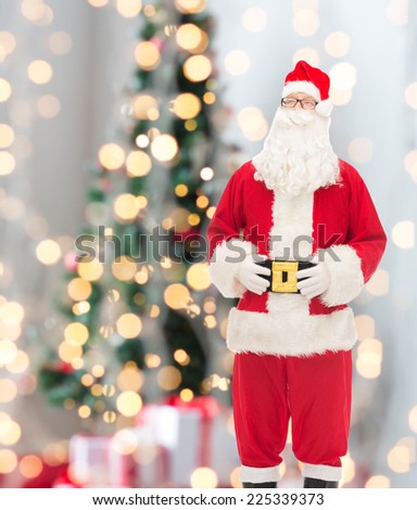 christmas, holidays and people concept - man in costume of santa claus over tree lights background