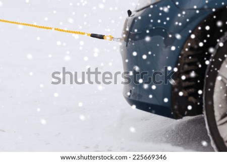 transportation, winter and vehicle concept - closeup of towed car with towing rope