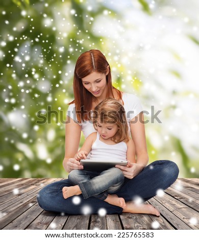 childhood, parenting, people and technology concept - happy mother with little girl and tablet pc computer over wooden floor and green plants background