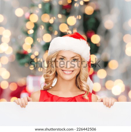 christmas, x-mas, people, advertisement and sale concept - happy woman in santa helper hat with blank white board over tree lights background