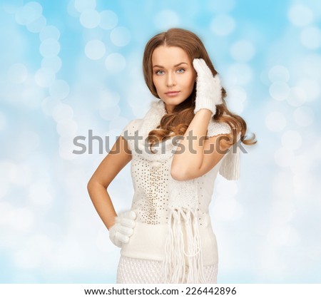 happiness, winter holidays, christmas and people concept - smiling young woman in white warm clothes over blue lights background