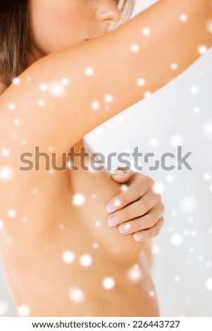 health, medicine, beauty and people concept - woman checking breast for signs of cancer over snowy background