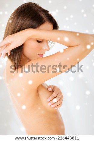 health, medicine, beauty and people concept - woman checking breast for signs of cancer over snowy background