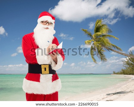 christmas, holidays, travel and people concept - man in costume of santa claus with notepad and pen over tropical beach background