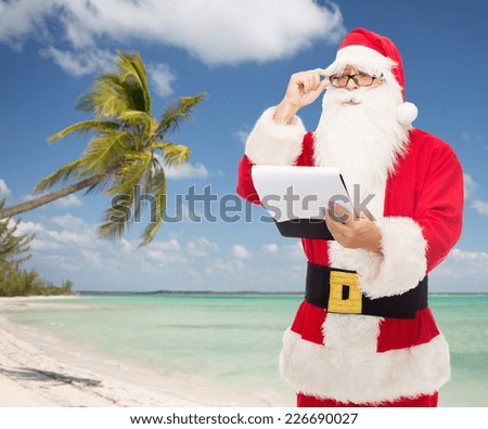 christmas, holidays, travel and people concept - man in costume of santa claus with notepad over tropical beach background