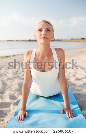 fitness, sport, people and lifestyle concept - young woman making yoga exercises lying mat outdoors