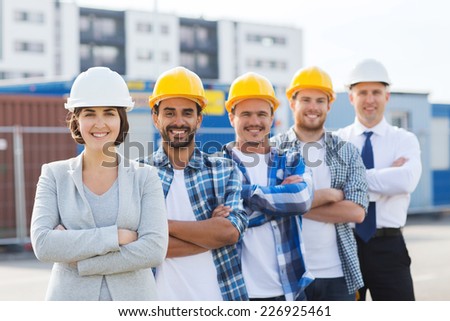 business, building, teamwork and people concept - group of smiling builders in hardhats outdoors
