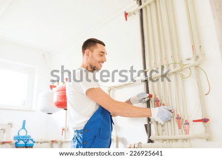 business, building, profession and people concept - smiling builder or plumber working indoors