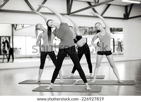 fitness, sport, training, gym and lifestyle concept - group of smiling women stretching in the gym