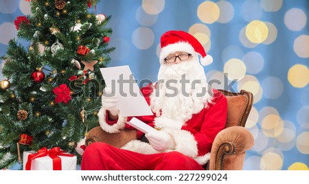 christmas, holidays and people concept - man in costume of santa claus with letter over blue lights background