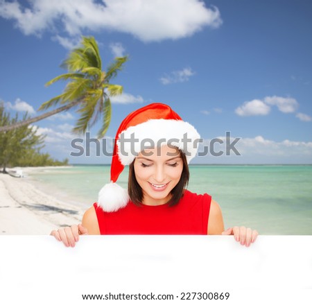 christmas, x-mas, people, advertisement and sale concept - happy woman in santa helper hat with blank white board over tropical beach background