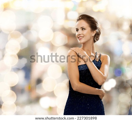 people, holidays and glamour concept - smiling woman in evening dress over lights background